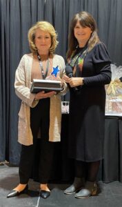 two women standing, woman on left with blonde hair woman on the right with brown hair